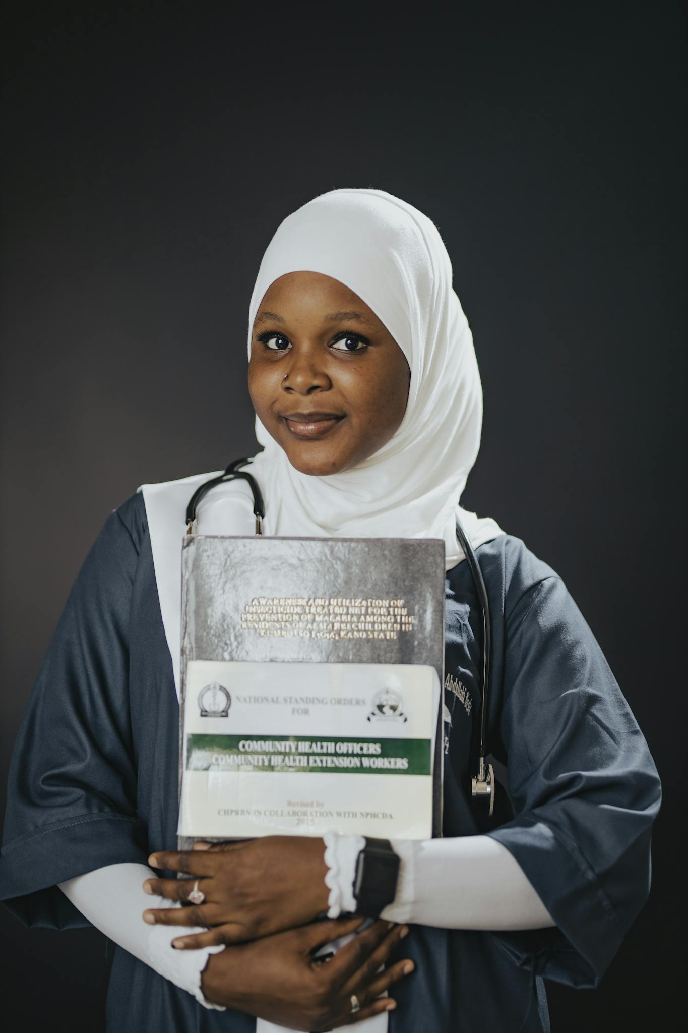 Confident young medical professional with books and stethoscope.