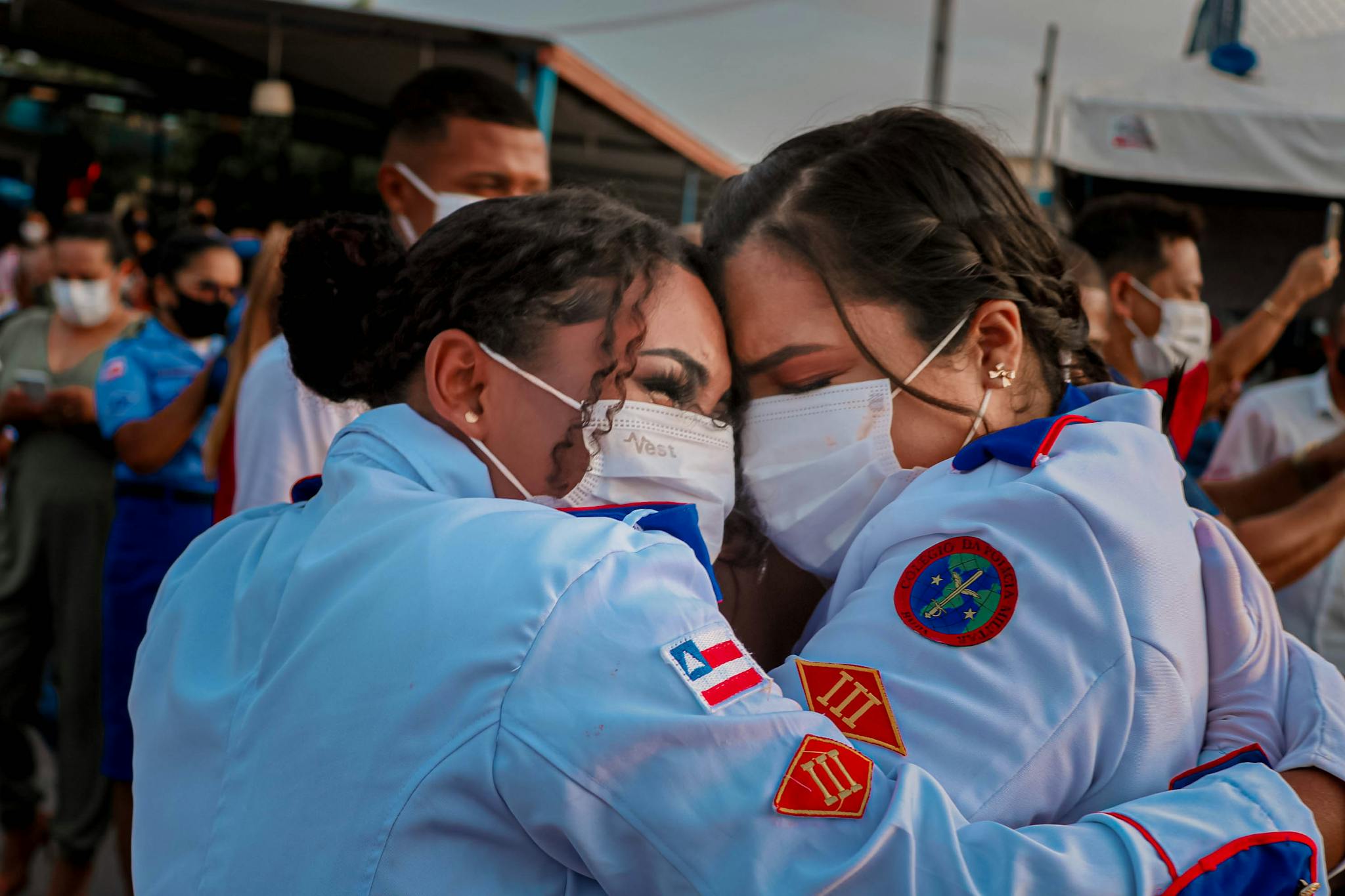 Women in uniforms embrace outdoors, celebrating and offering support and unity.
